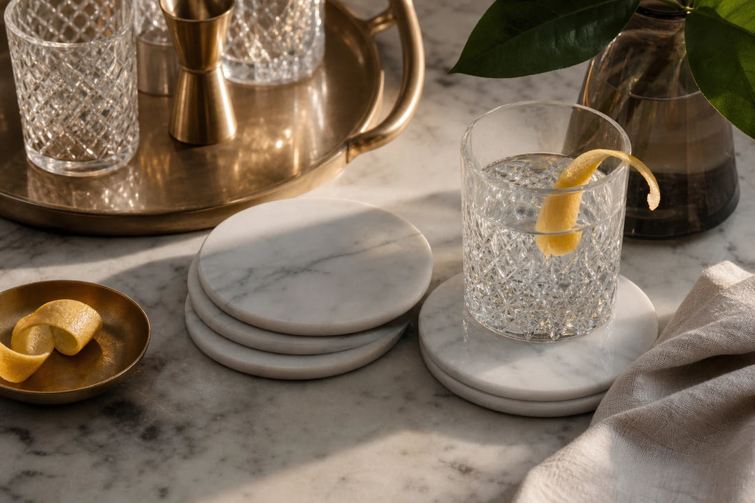 Carrara marble coasters styled with glassware and linen on a TATPUB hosting surface.