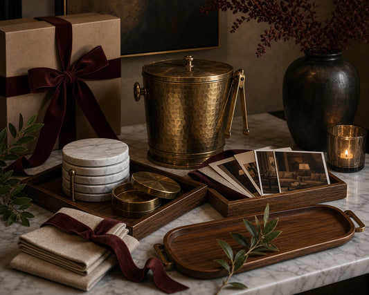 A TATPUB giftable host objects arrangement with marble coasters, teak tray, brass ice bucket, hosting cards, and linen paper.