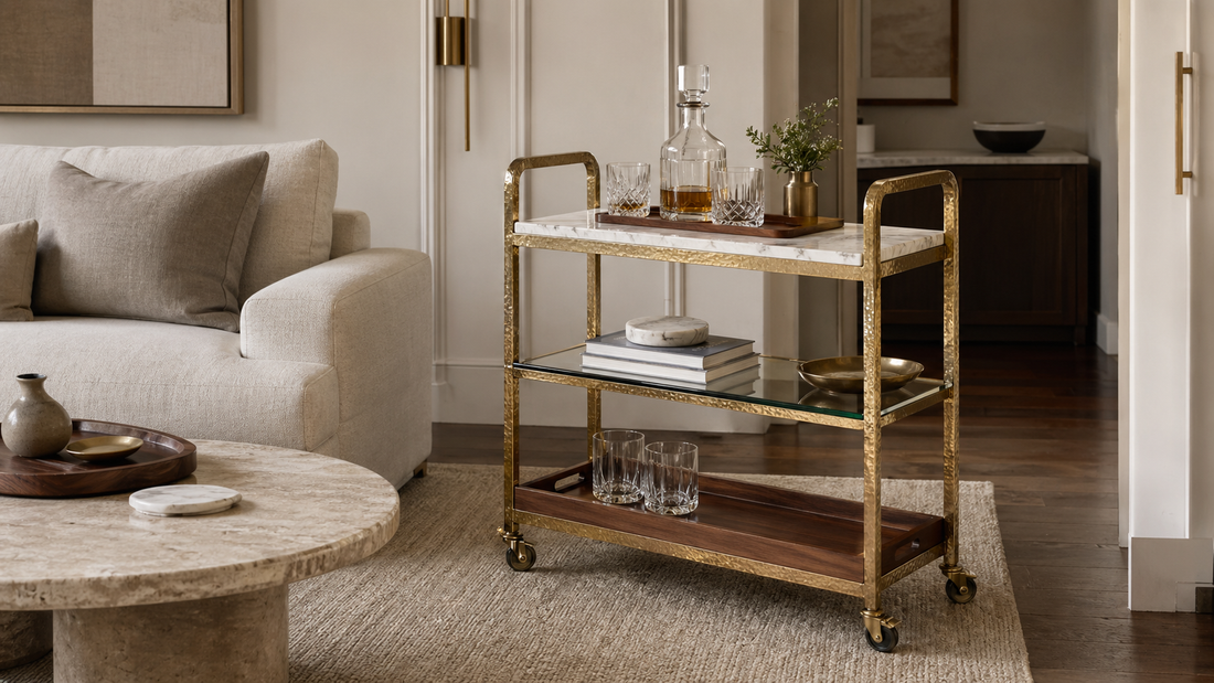 A living room bar cart styled with marble coasters, a teak tray, glassware, and quiet-luxury furniture details.