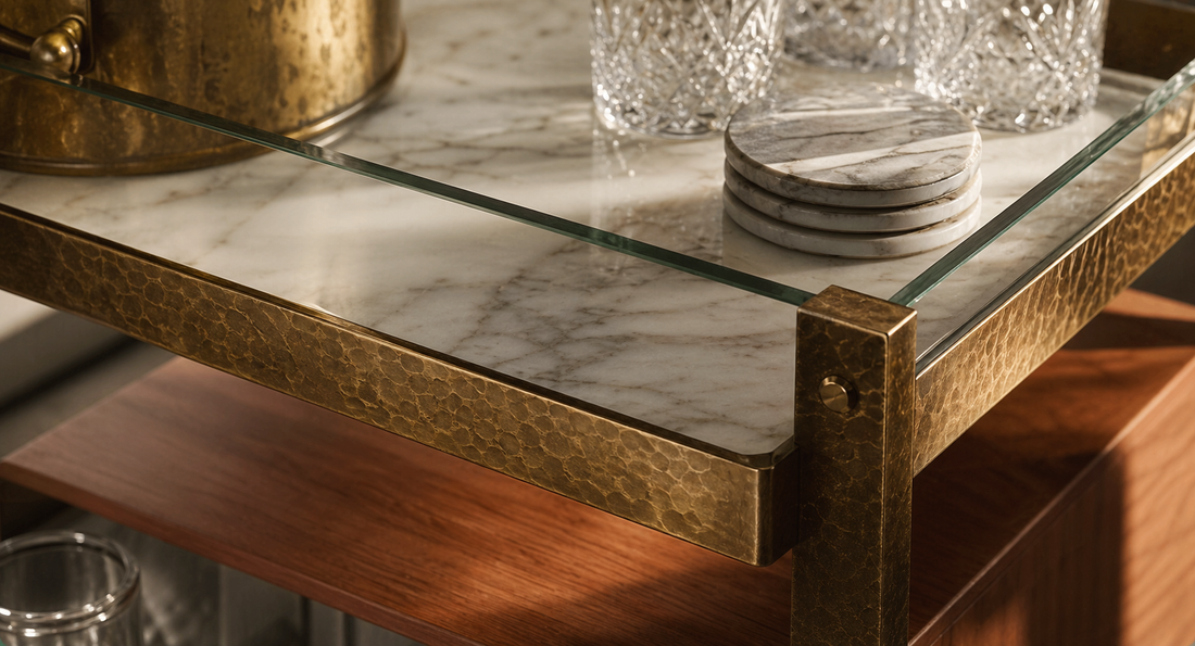 Close detail of marble, hammered brass, tempered glass, and teak material language on a TATPUB hosting system.