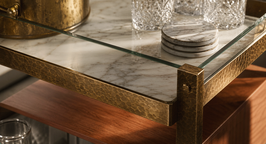 Close detail of marble, hammered brass, tempered glass, and teak material language on a TATPUB hosting system.