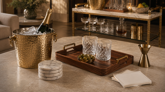 A modern host gift guide scene with TATPUB marble coasters, teak tray, brass ice bucket, hosting cards, and hosting system.