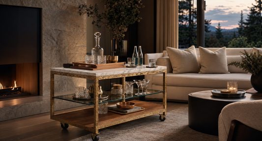 A quiet-luxury living room with the TATPUB marble and hammered brass hosting system styled as a built-in service moment.